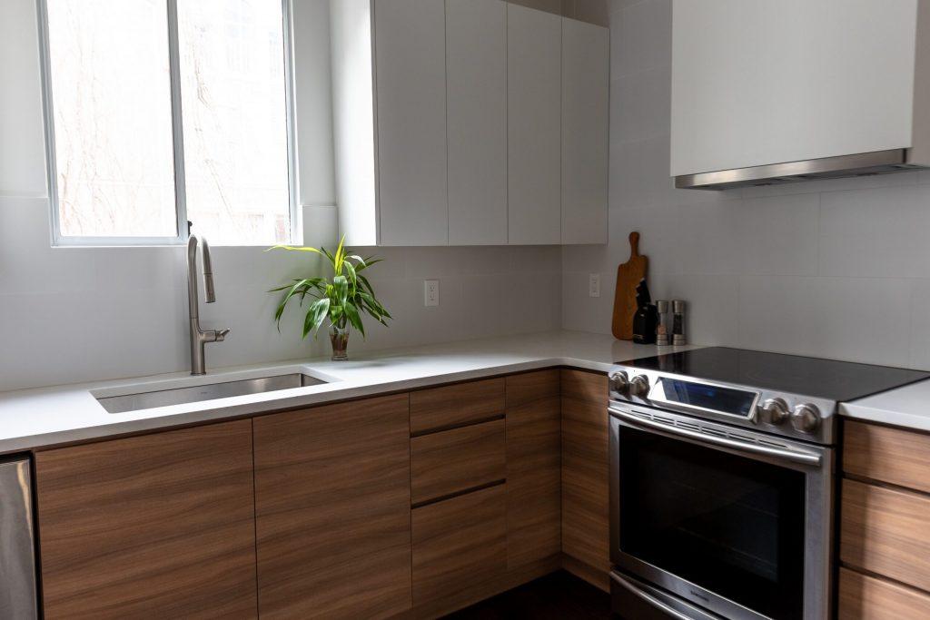 Handleless walnut-grain lowers and white slab uppers with quartz countertops and a stainless range, Vancouver kitchen renovation