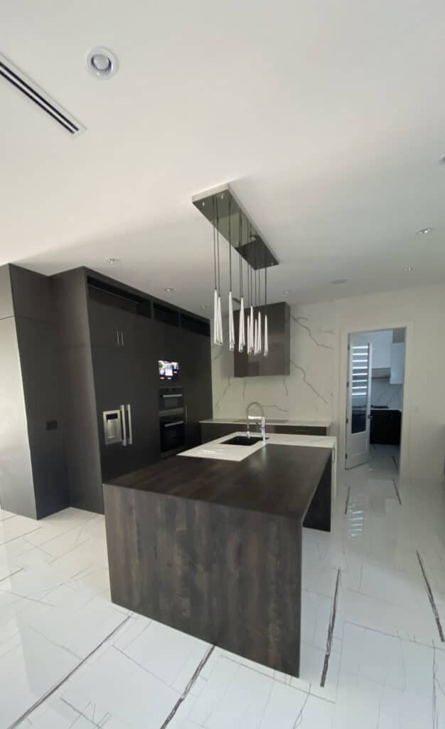Dark oak laminate kitchen with a quartz and butcher-block style waterfall island, Calacatta quartz slab backsplash and Miele appliances, Deer Lake kitchen renovation in Burnaby